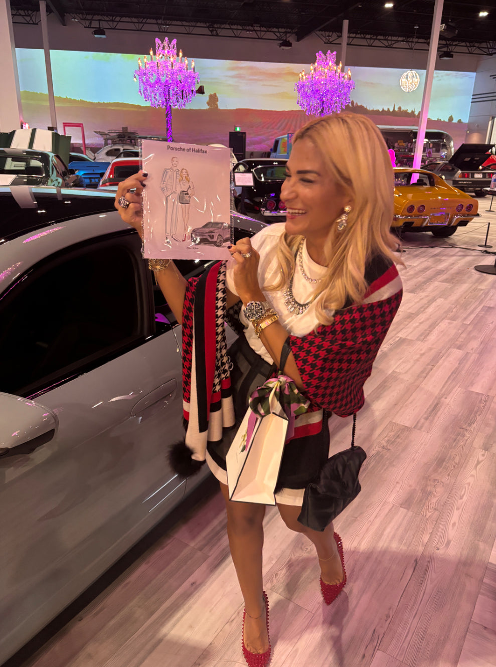Woman holding a Nina Maric fashion illustration  in a car showroom