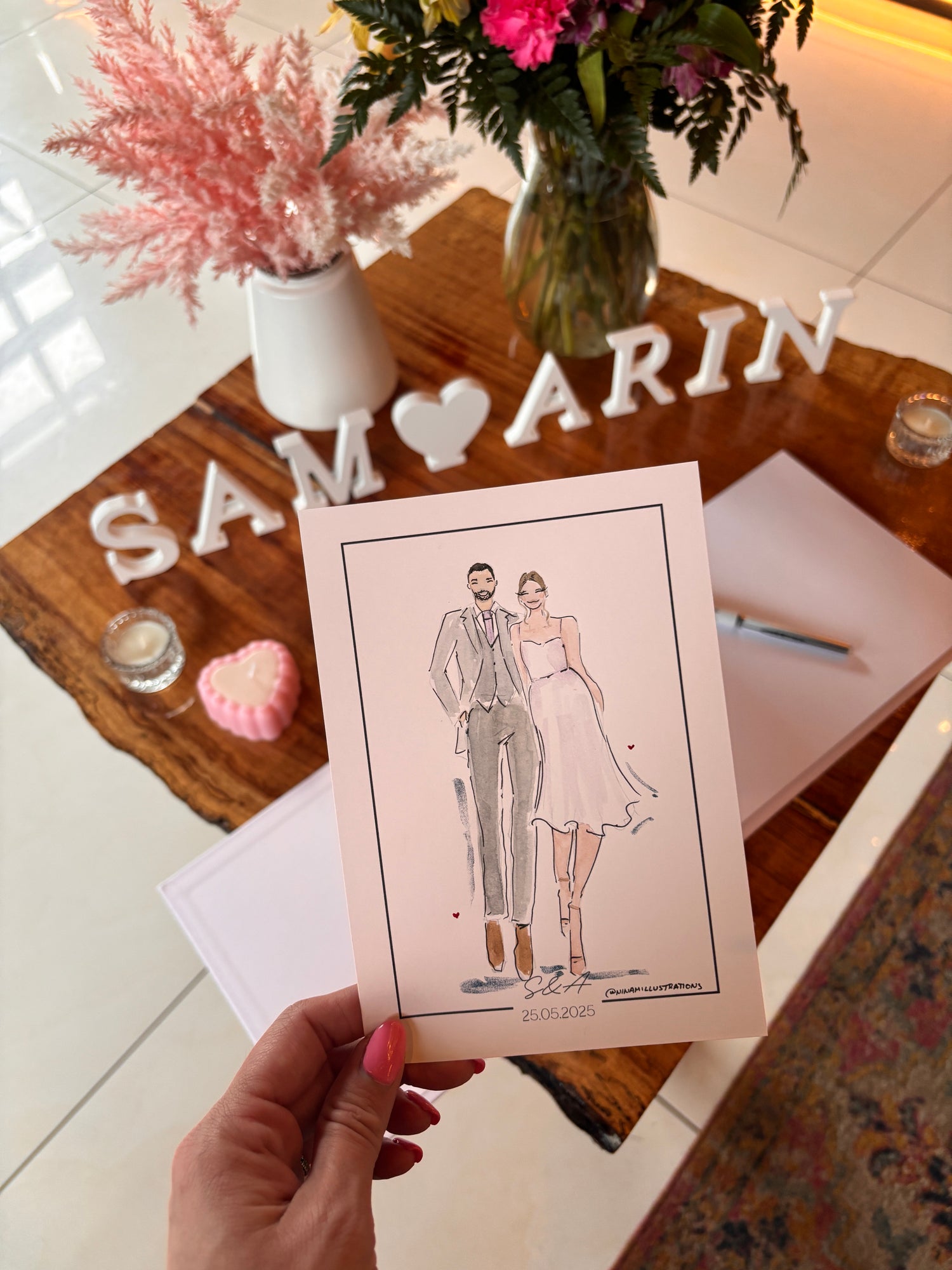 Hand holding a card with a couple illustration on a decorative table.