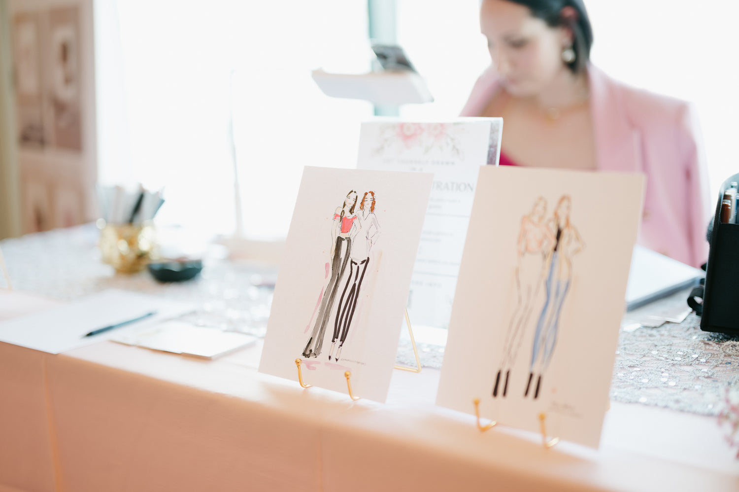 Two fashion sketches on a desk with a blurred background of Nina Maric artist