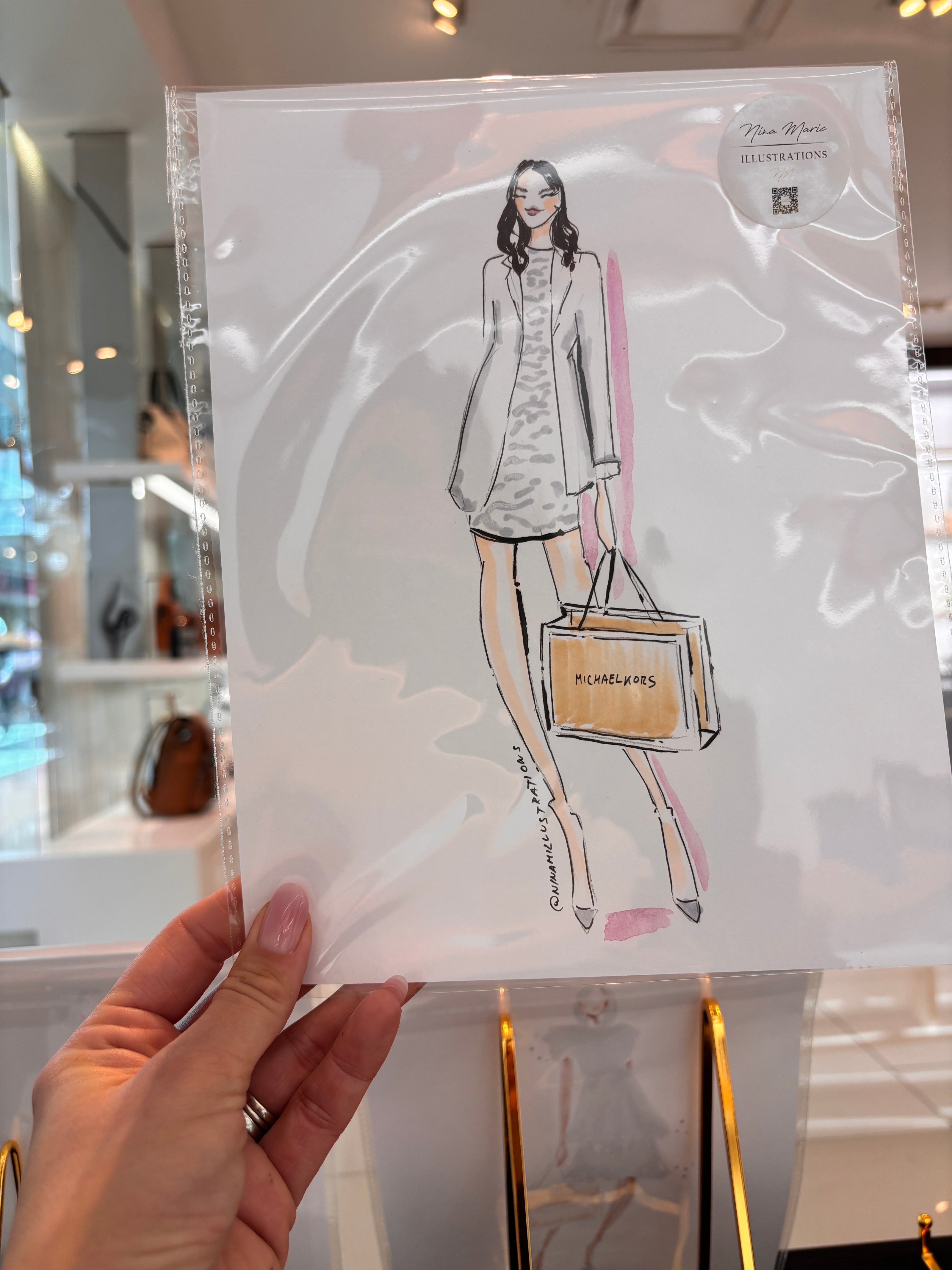 Illustration by Nina Maric of a woman holding a handbag with a hand holding it, on a white card.
