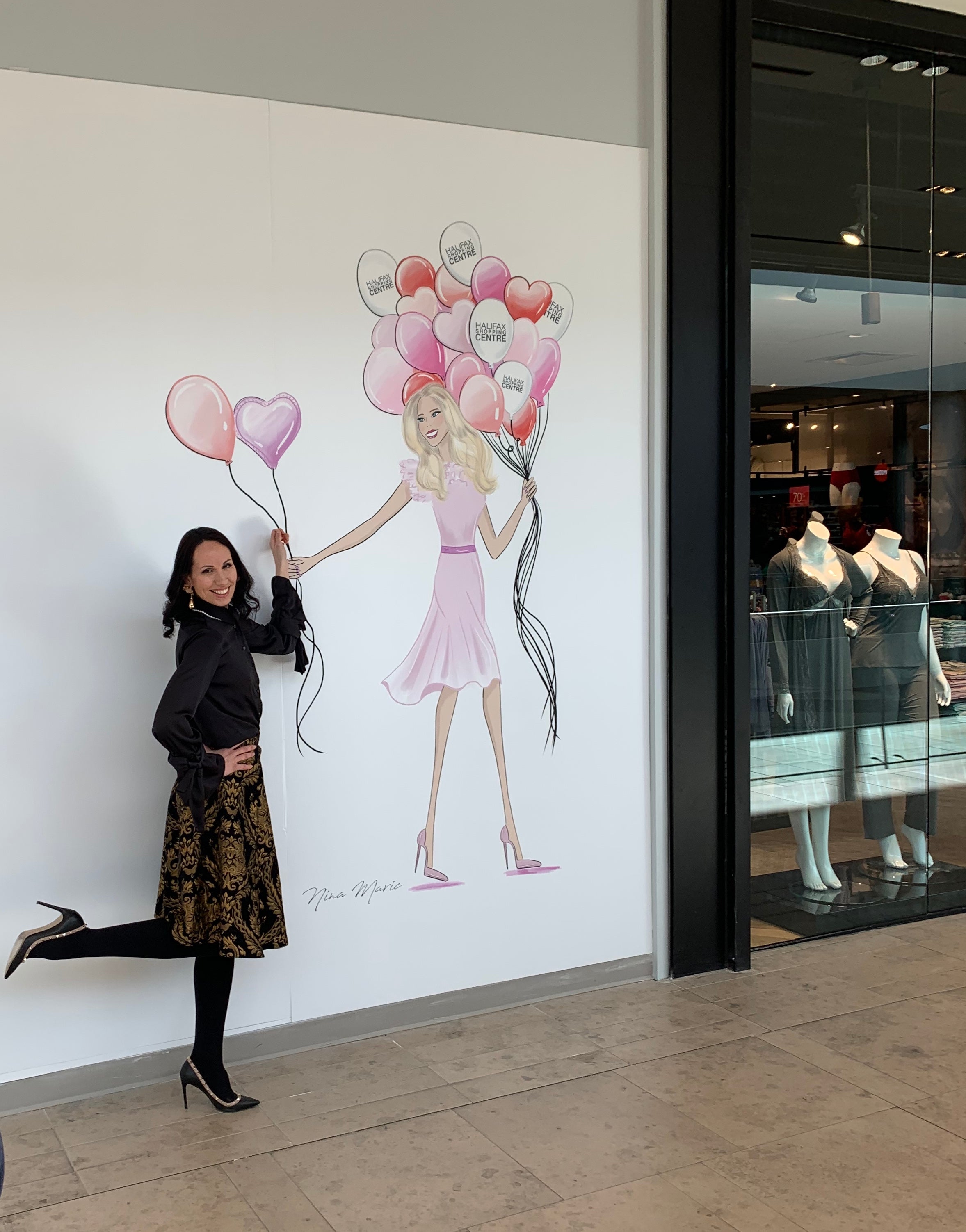 Nina Maric posing next to a custom wall mural in Halifax Shopping Centre