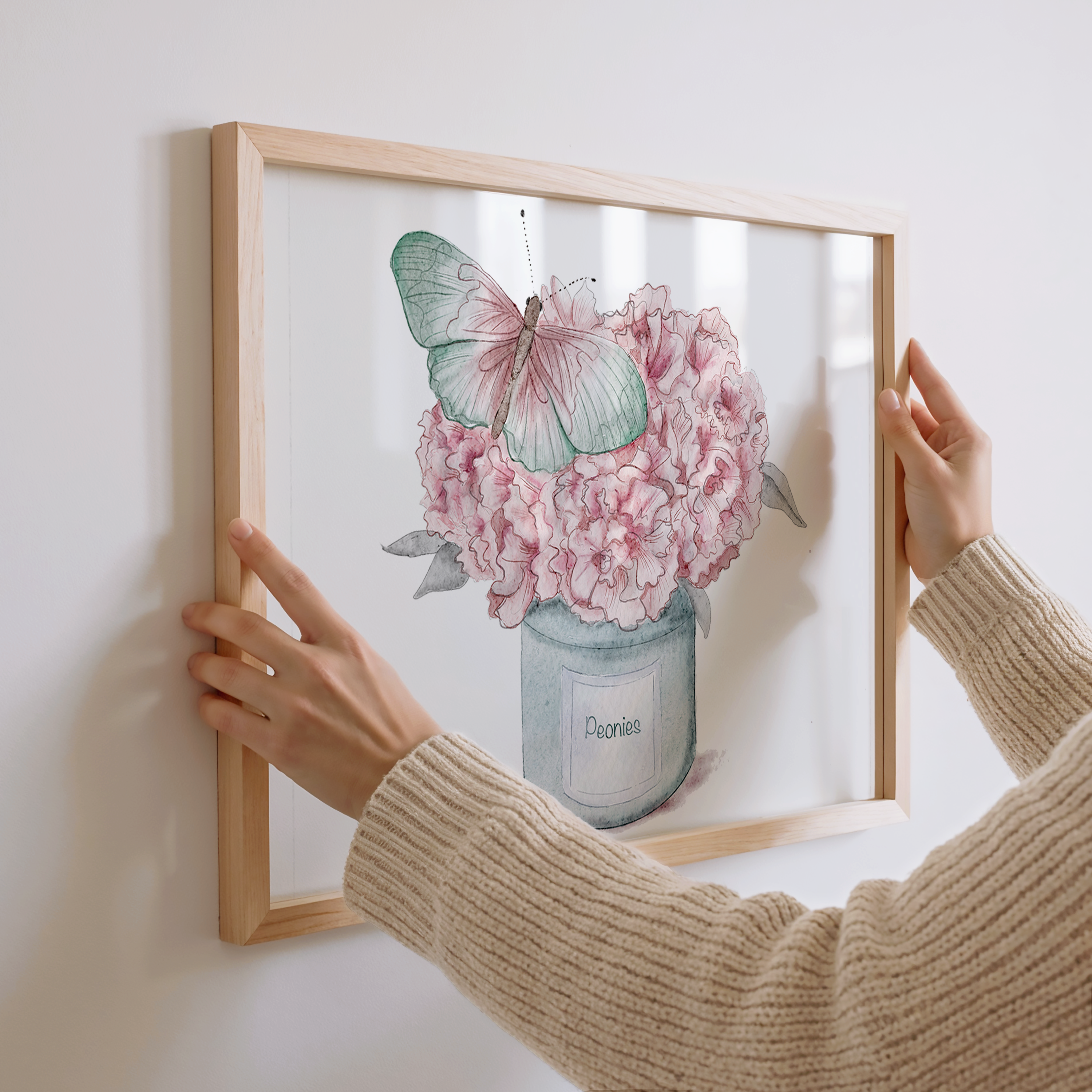 Nina Maric holding a framed artwork of pink flowers and a butterfly.