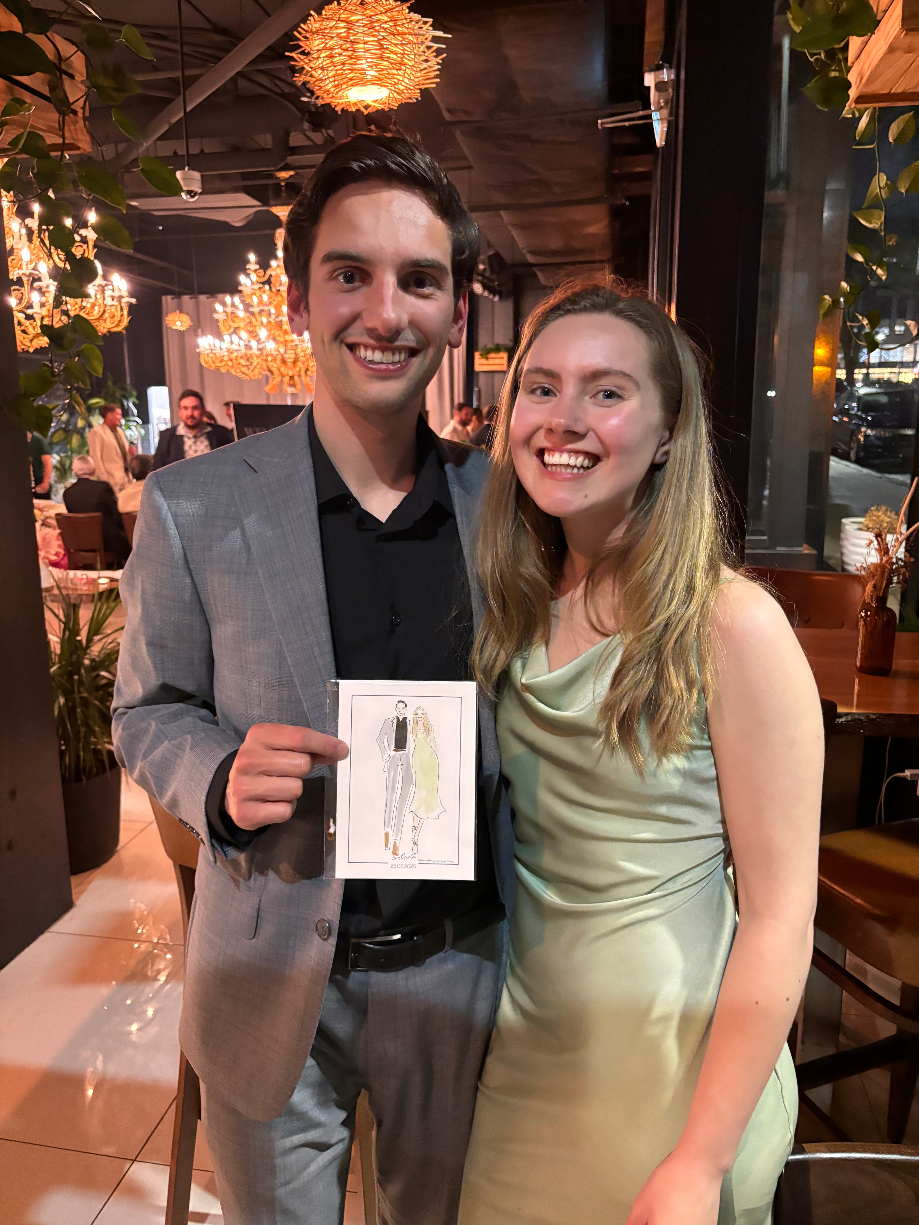 Two people holding live sketches at a wedding
