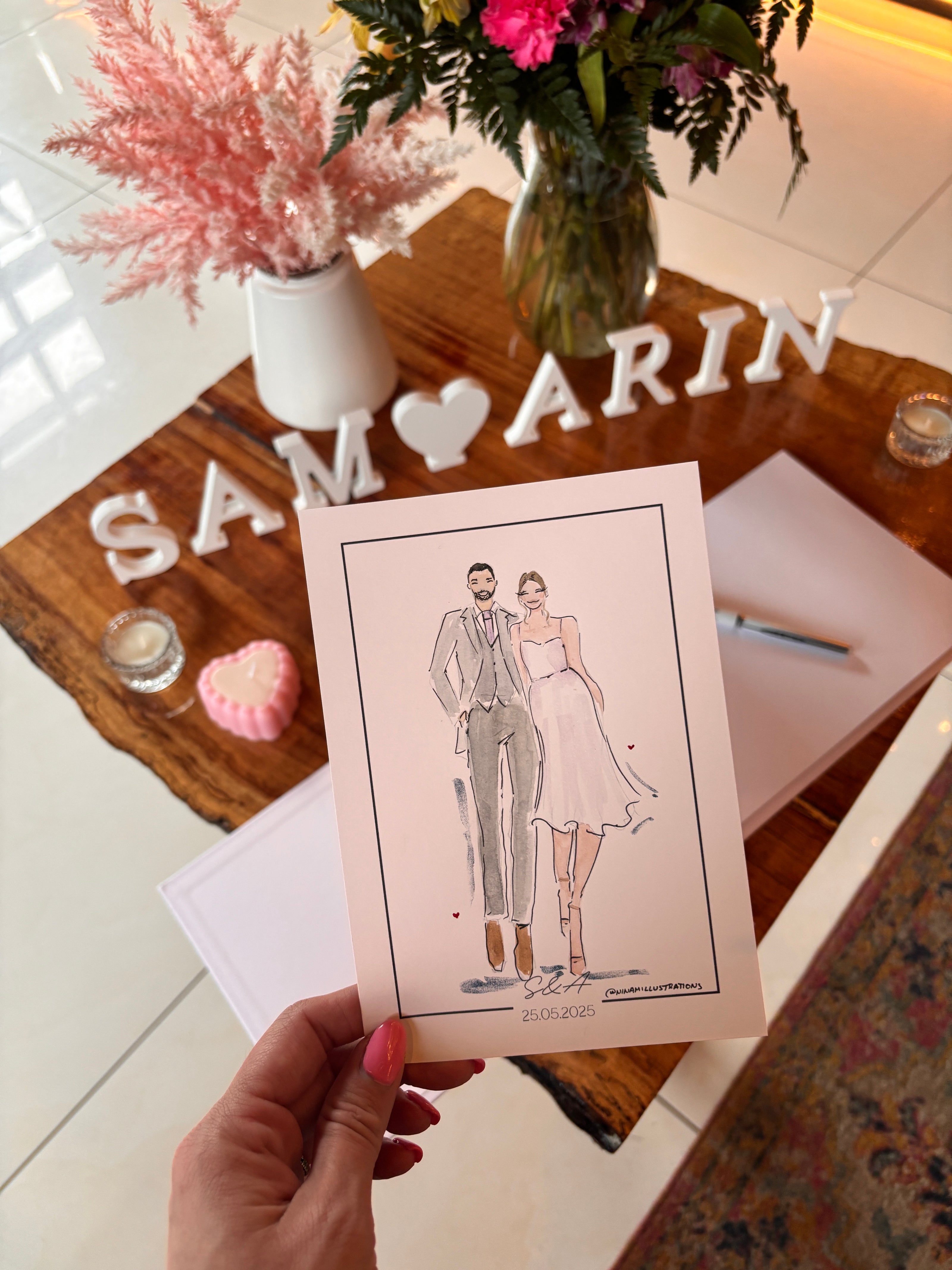 Hand holding a card with a couple illustration on a decorative table.